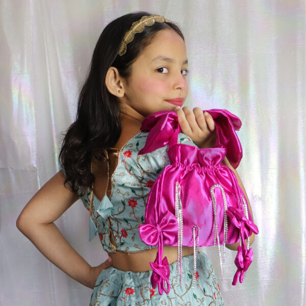 A close-up image of a small pink potli bag for kids, featuring a drawstring closure and a cute bow handle